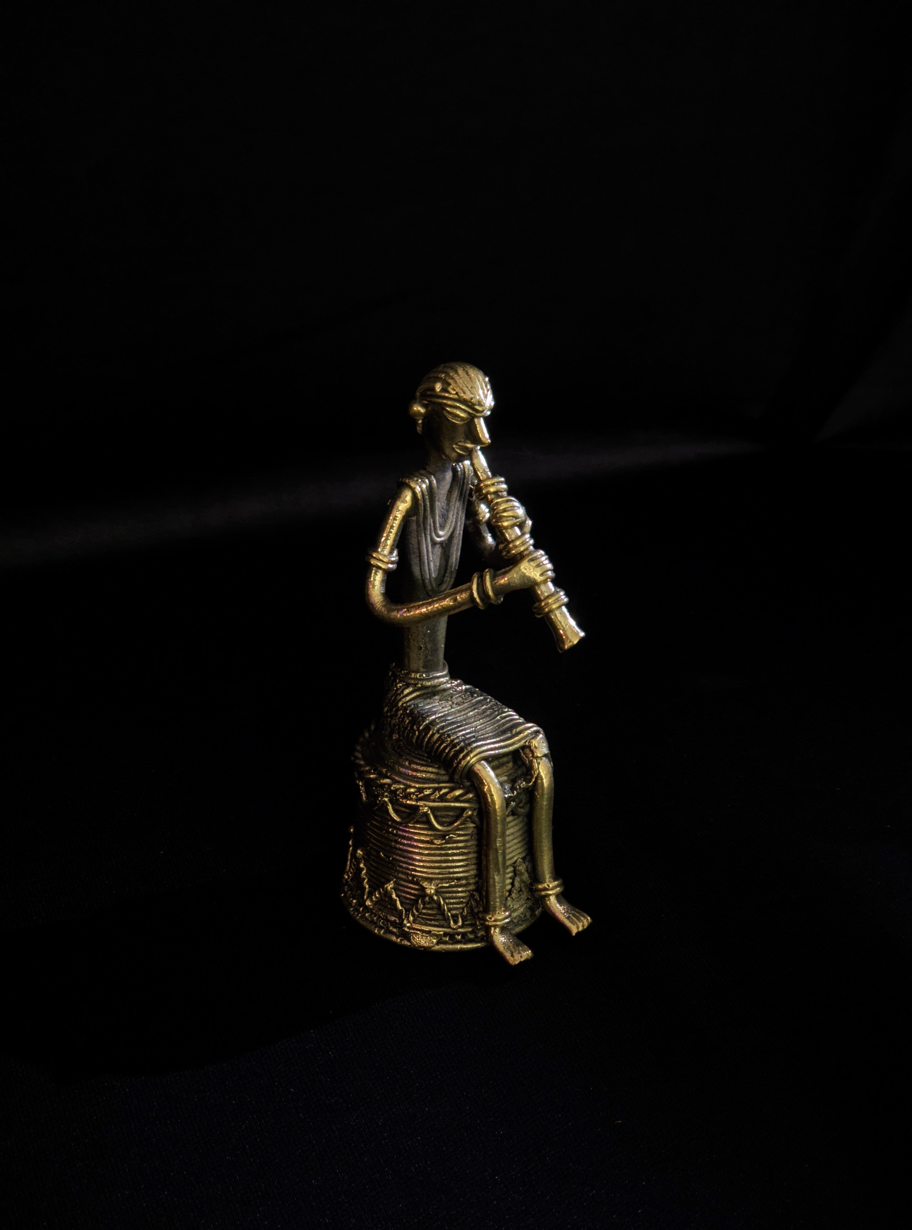 Dhokra - Tribal Musician sitting on base playing Turi