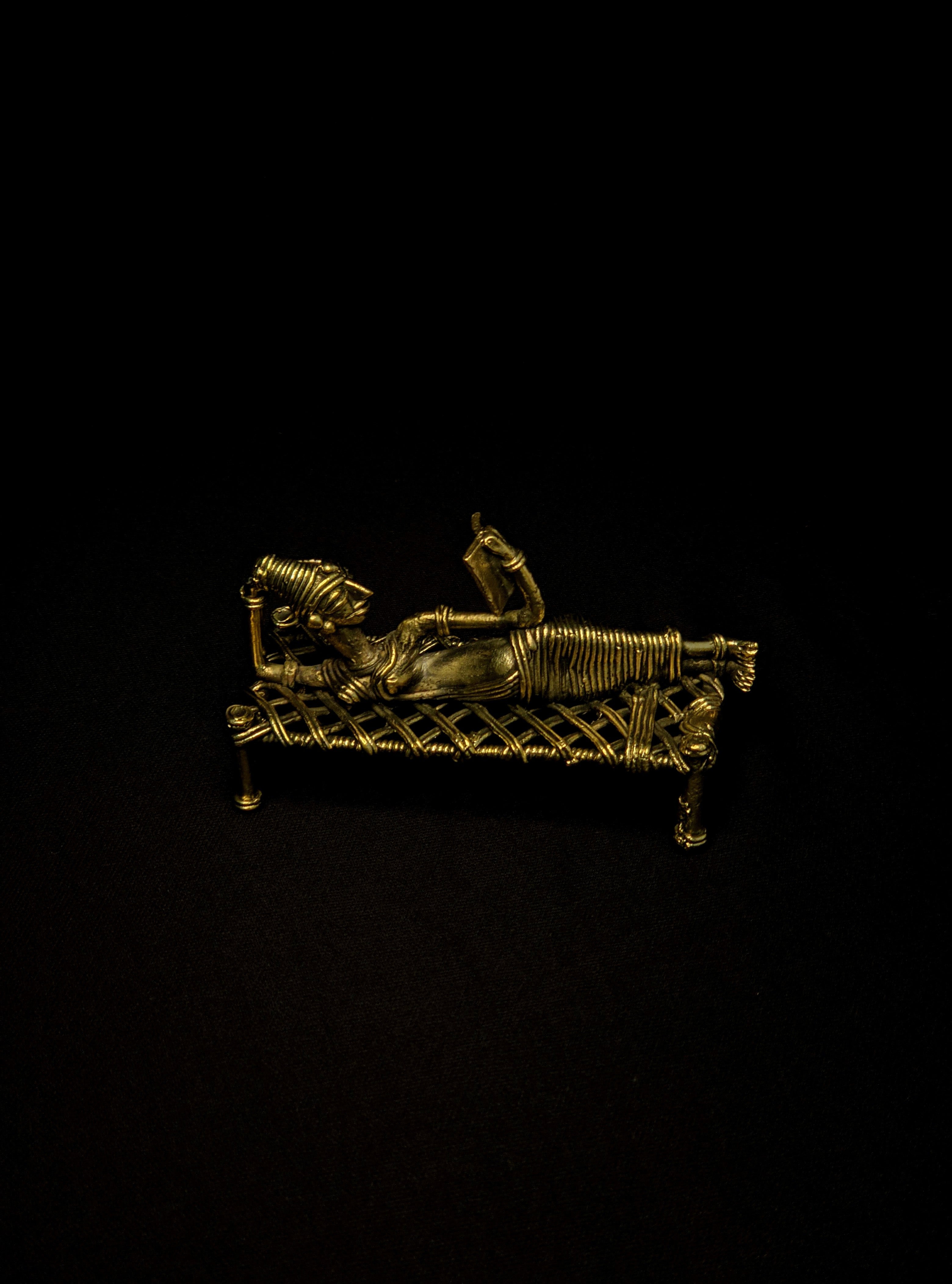 Dhokra - Tribal Lady sleeping on bed and reading